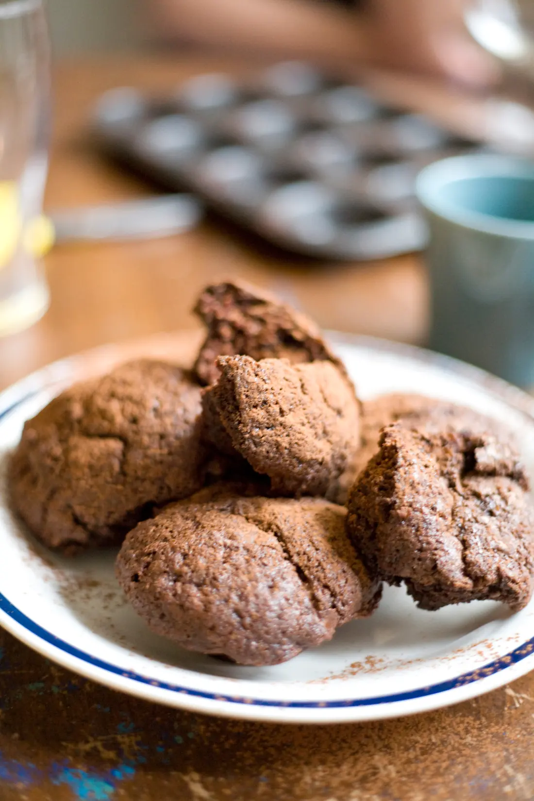 Four chocolate muffins on a blue-rimmed plate